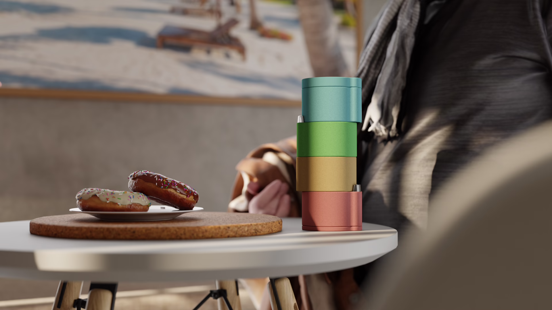 Giocuosa with four modules in teal, green, ochre and coral, on a small table beside a plate of doughnuts