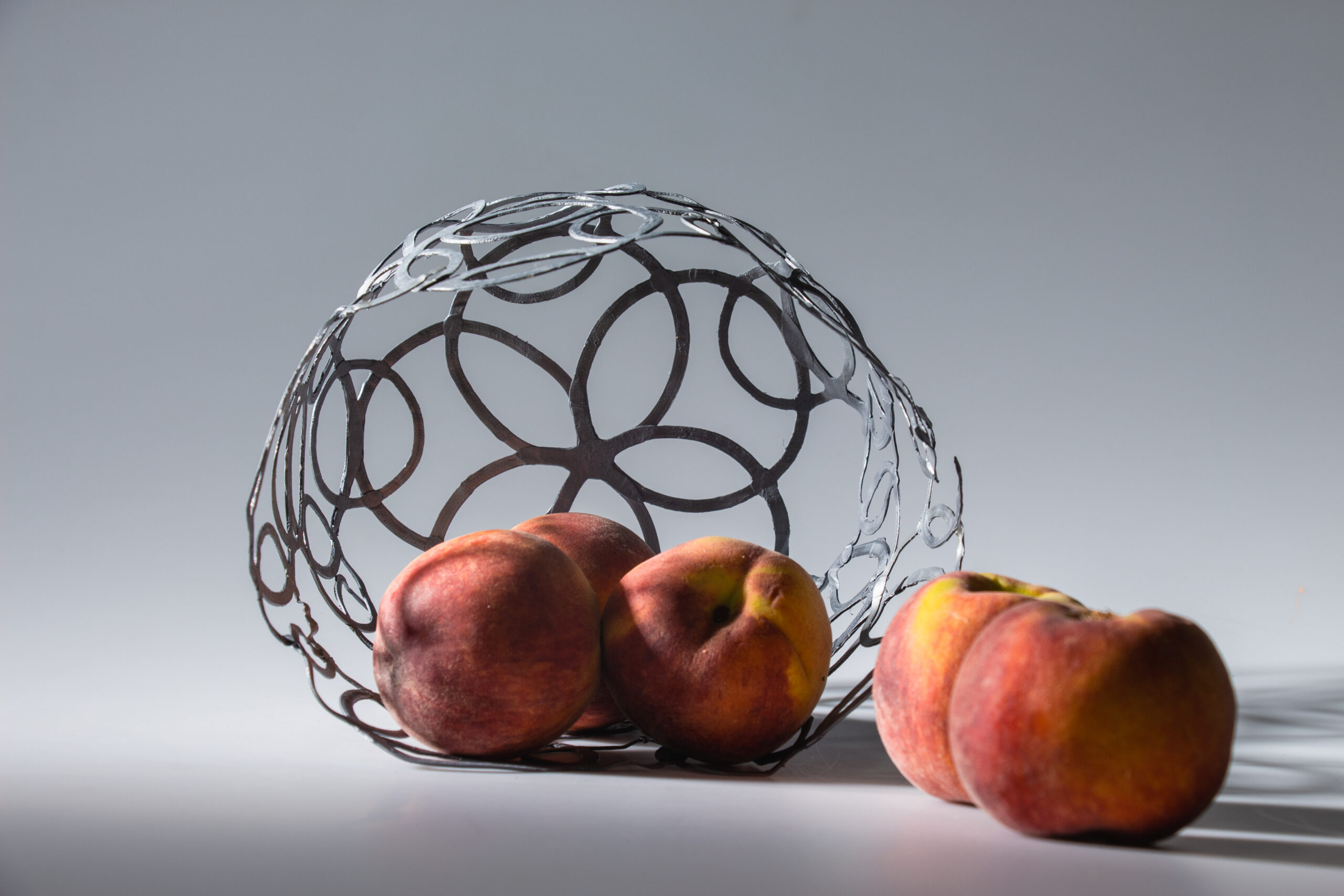 The PLArt fruit bowl lying on its side, with peaches inside